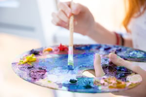 Closeup of paintbrush in woman hands mixing paints on palette - structured innovation requires creative thinking